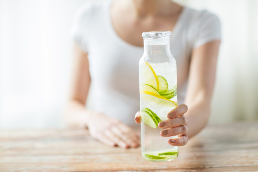 A woman offering a glass of lemon water