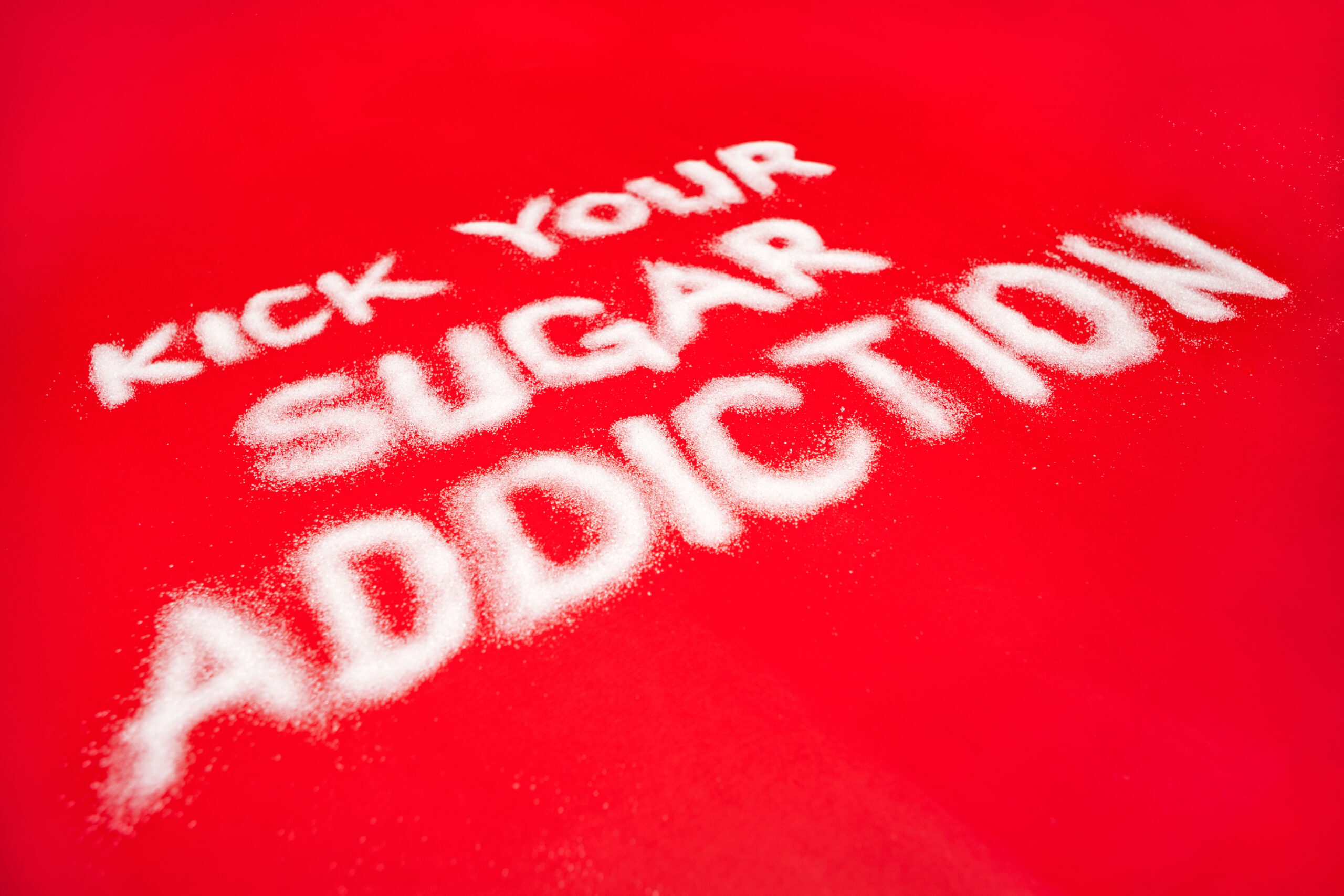 "Kick Your Sugar Addiction" spelt out on a orange table in sugar.