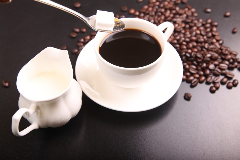 Sugar being added to a cup of coffee.