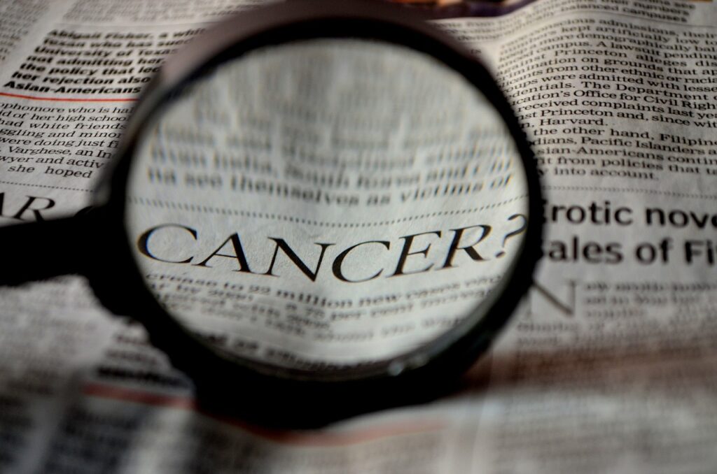 A magnifying glass focusing on the word cancer in a newspaper