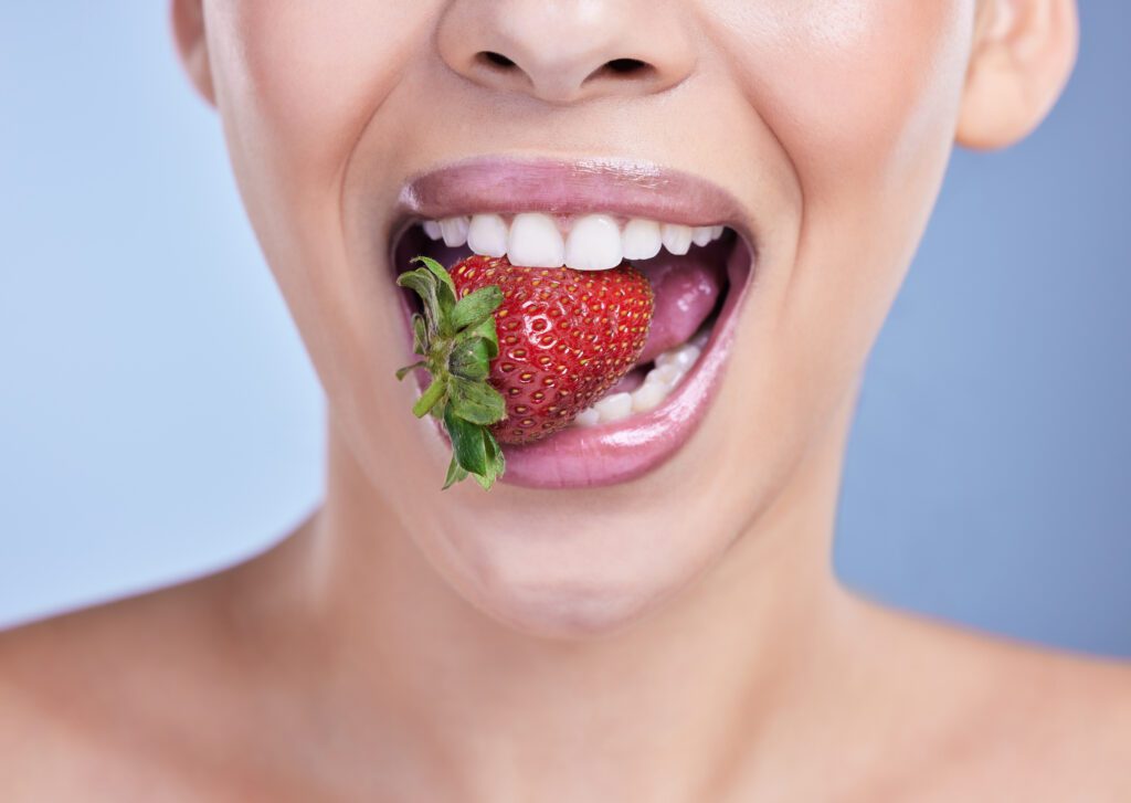 A woman with youthful looking skin eating a strawberry