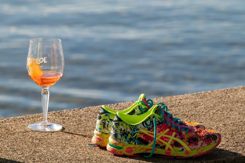 An alcoholic drink and running shoes laying next to each other.