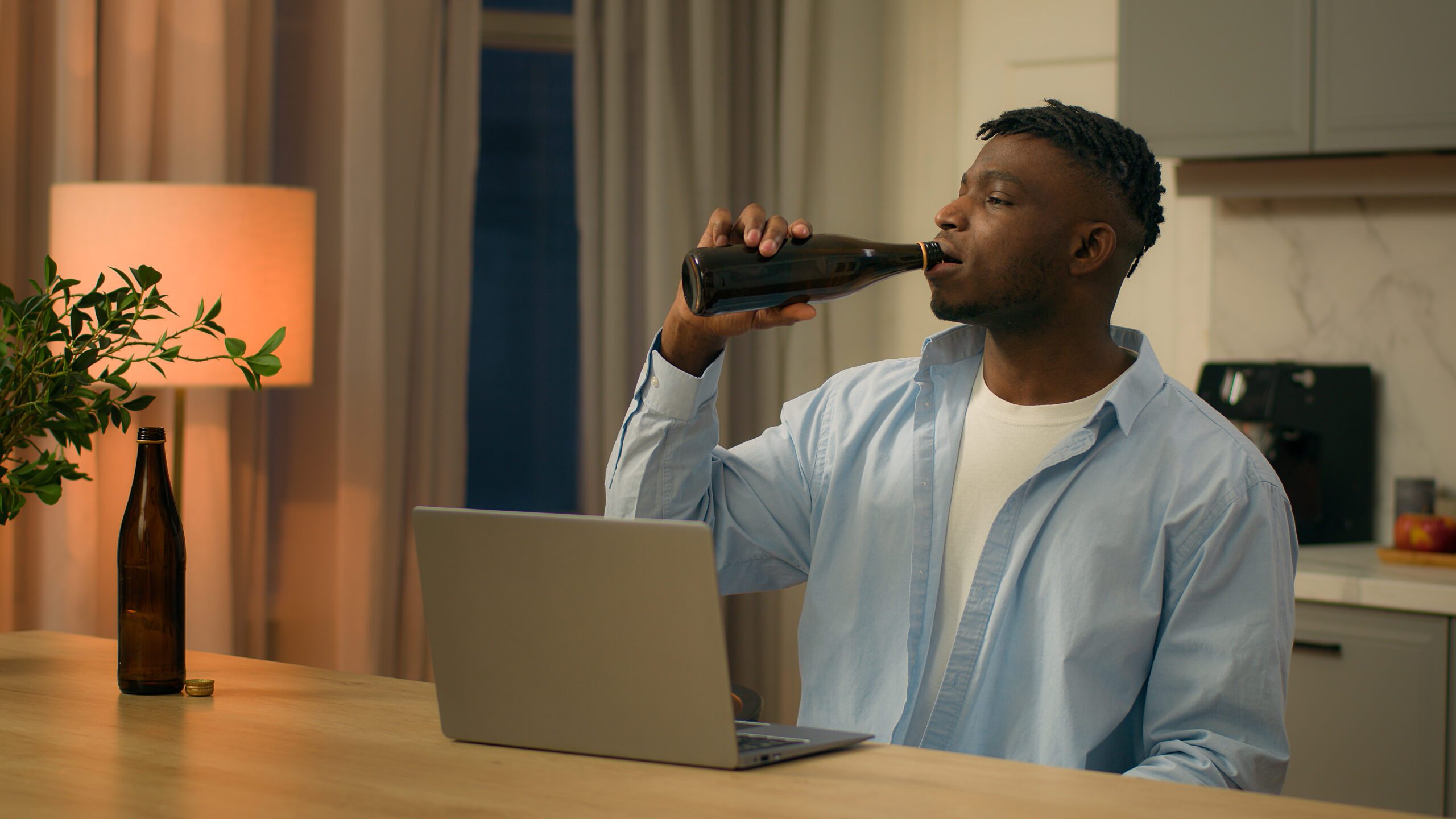 A man drinking an alcoholic beverage in the evening to highlight a bad habit