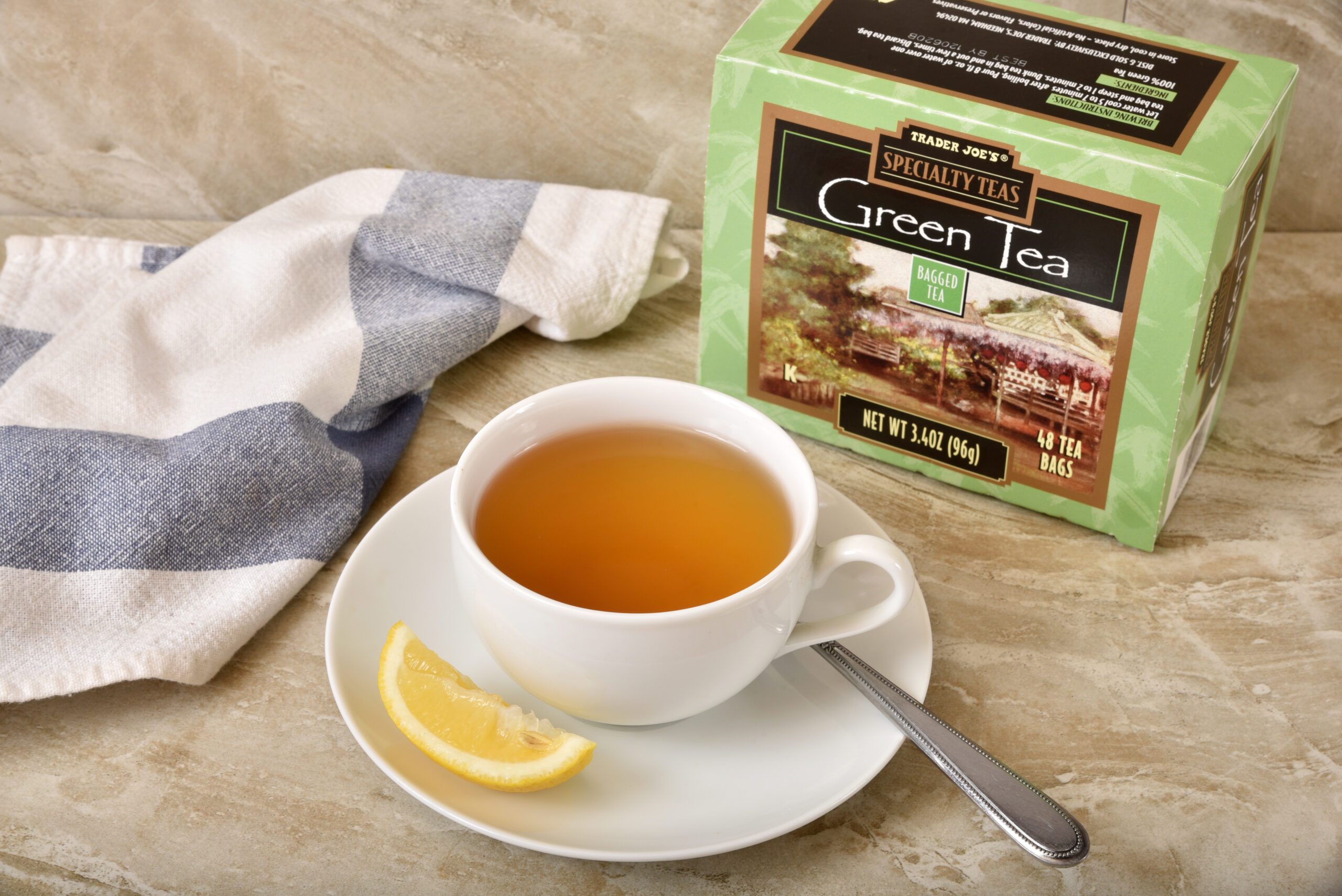 A cup of green tea next to a box of green tea