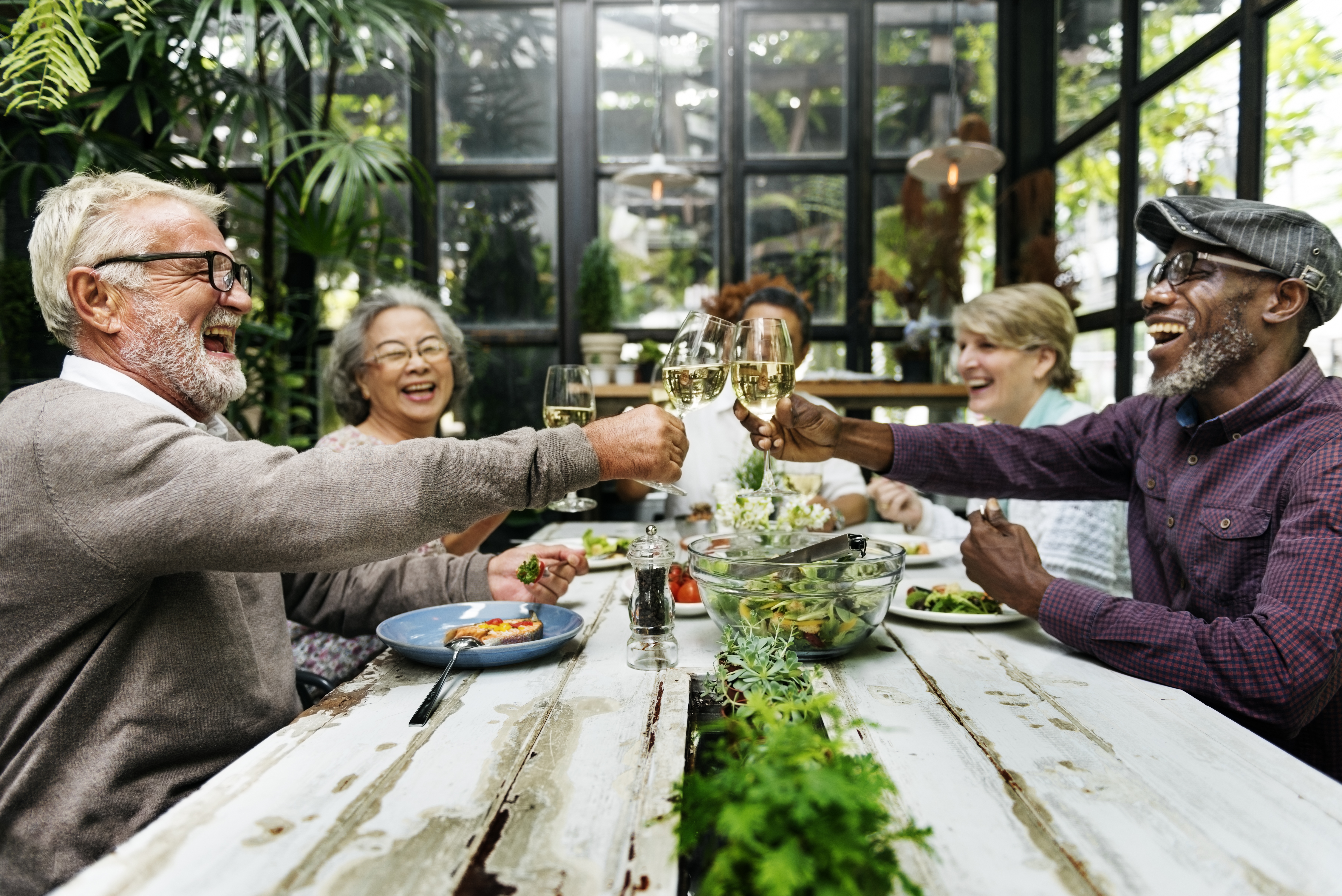 A group of happy people being grateful for each others company as they cheers at a table with food.