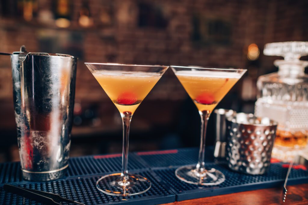 Two alcoholic drinks, cocktails, sitting on a bar table.