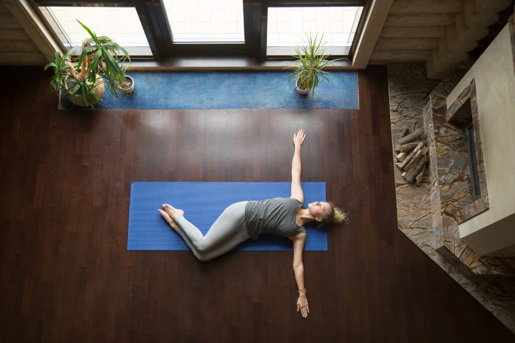 A woman performing a supine twist back stretch