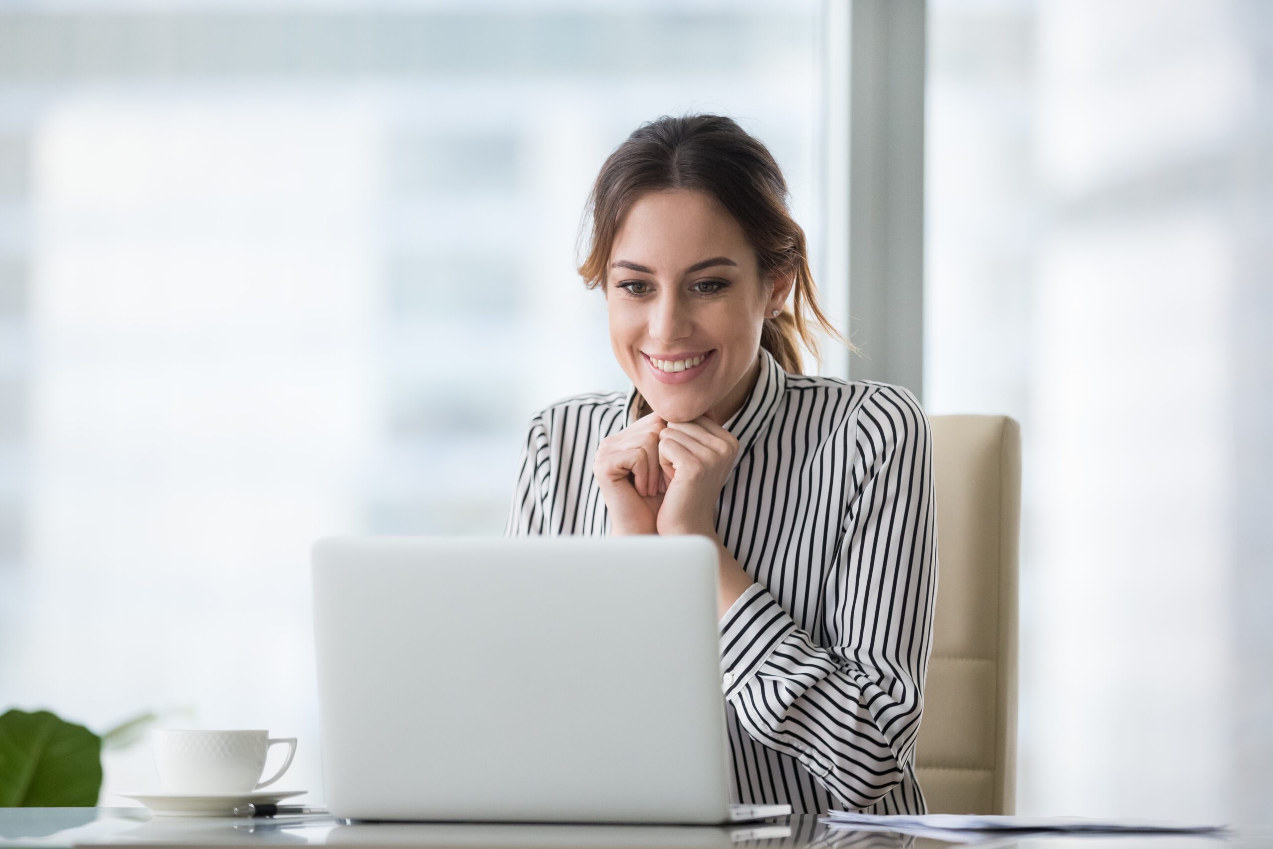 A woman smiling at her laptop.