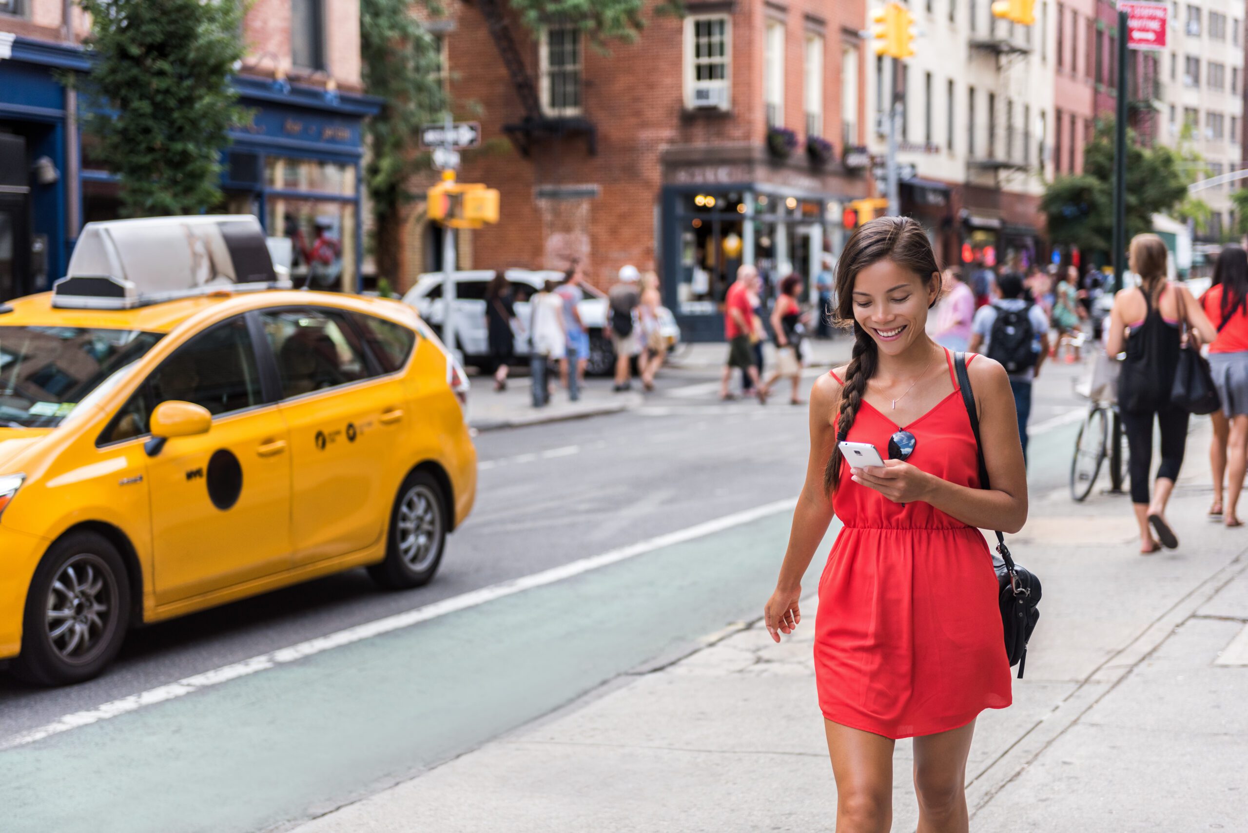 A woman walking down a busy city street during the day.