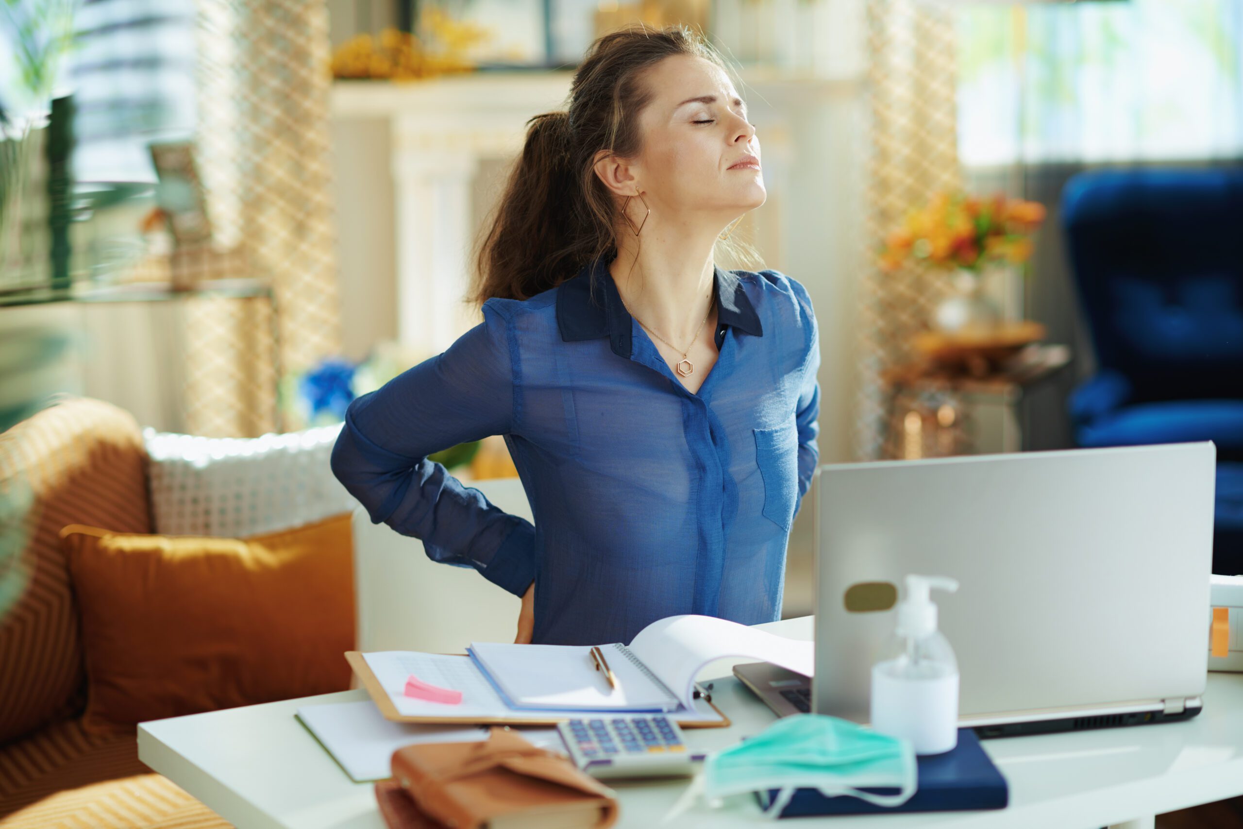A woman sitting at a desk experiencing back pain