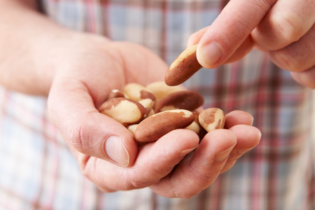 A man holding a handful of seemingly healthy nuts which are calorie dense